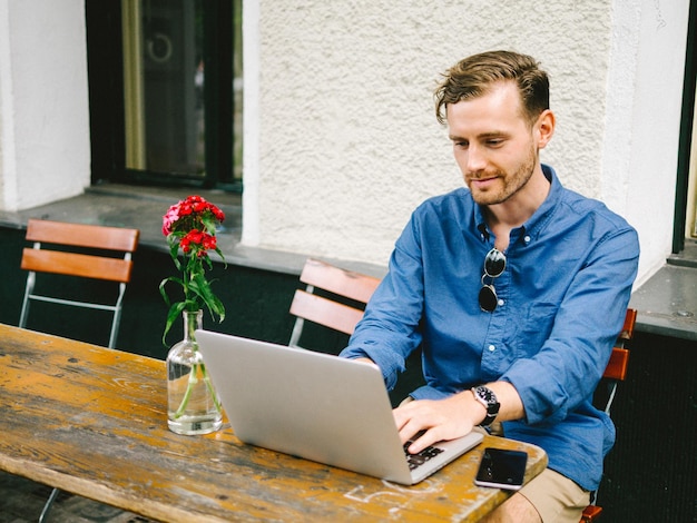 Young man using laptop at outdoors cafe