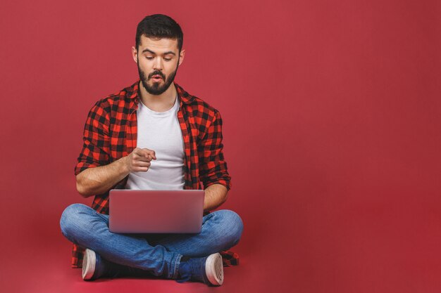 Foto giovane che per mezzo di un computer portatile e sedendosi sul pavimento