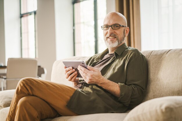 家のソファに座っている若い男がラップトップを使っている