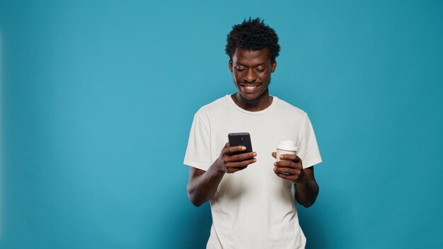 Photo young man using mobile phone against blue background