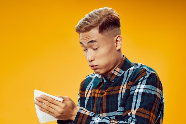 Young man using mobile phone against yellow background