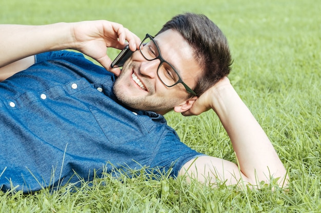 Young man using mobile phone while lying on grass