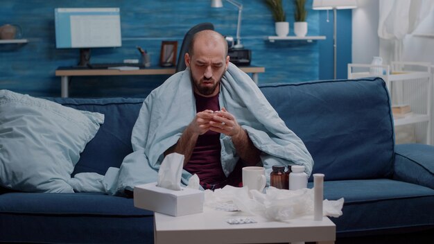 Photo young man using mobile phone while sitting on bed at home