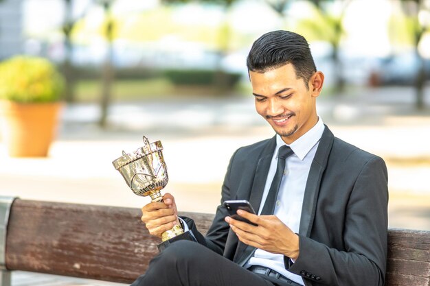 Photo young man using mobile phone while sitting outdoors
