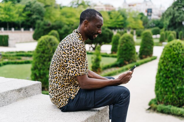 Young man using mobile phone while sitting outdoors