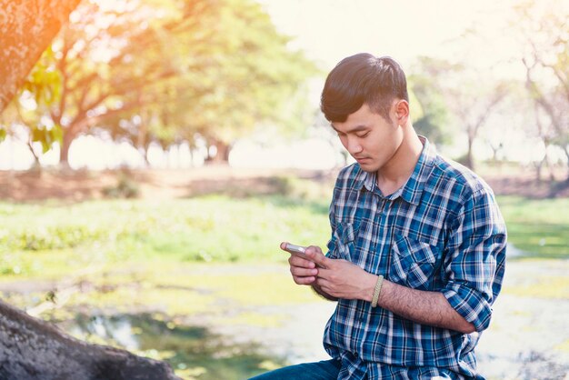 写真 若い男が屋外に座って携帯電話を使っている