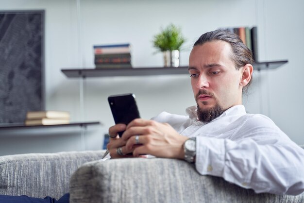 Young man using mobile phone while sitting on sofa at home