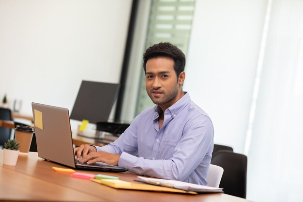 Photo young man using mobile phone while sitting on table