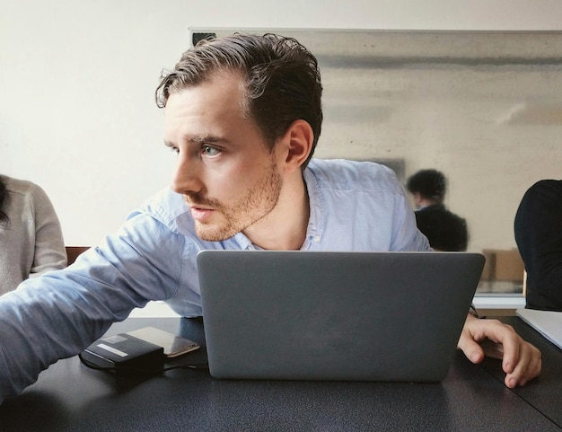 Young man using mobile phone while sitting on table