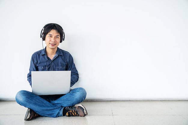 Photo young man using mobile phone while sitting on wall