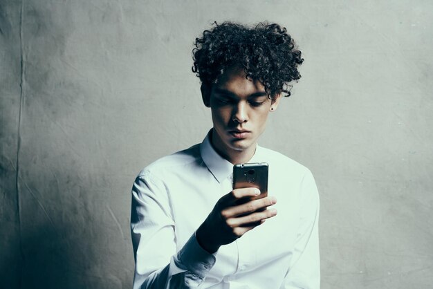 Young man using mobile phone while standing against wall