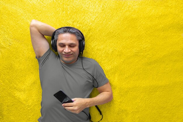 Young man using mobile phone while standing against yellow wall