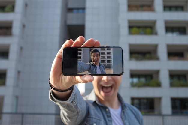 Photo young man using mobile phone while standing outdoors