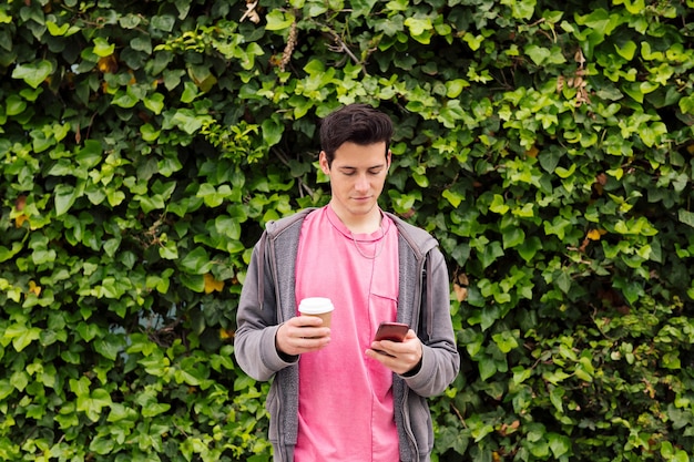 Young man using phone on a plants background