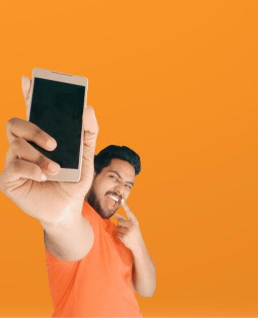 Young man using smart phone against orange background