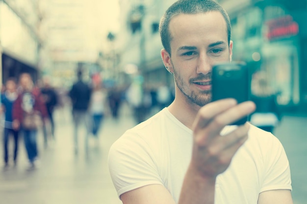 Young man using smart phone while standing on city street