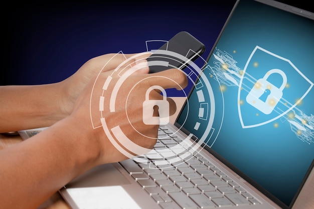 Photo young man using a smartphone and computer laptop. cyber internet security system. lock icon security technology on computer laptop screen.