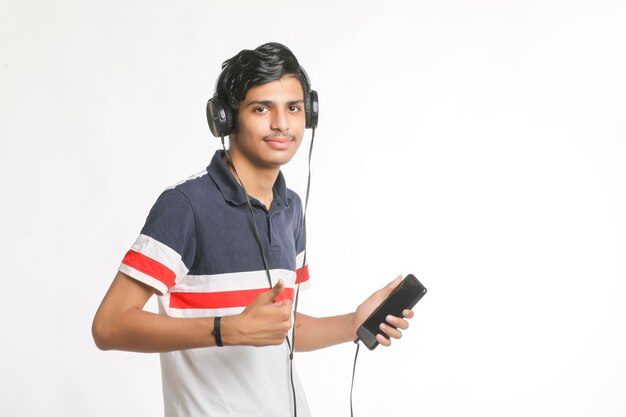 スマートフォンとヘッドフォンの付属品を使用して若い男。