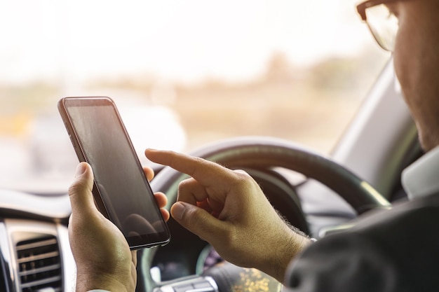 Young man using smartphone while driving car. Using a smartphone while driving is at risk of being involved in accidents and dangerous.