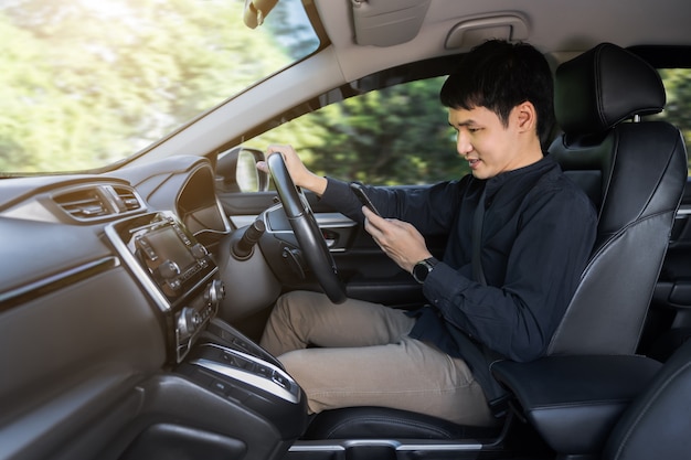 young man using a smartphone while driving a car