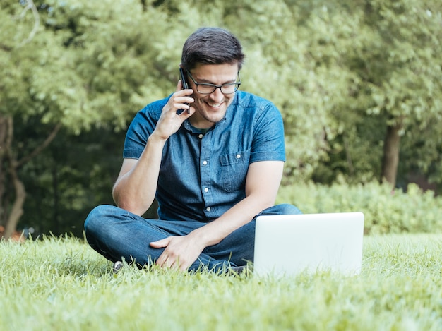 Young man using smartphone while sitting on grass