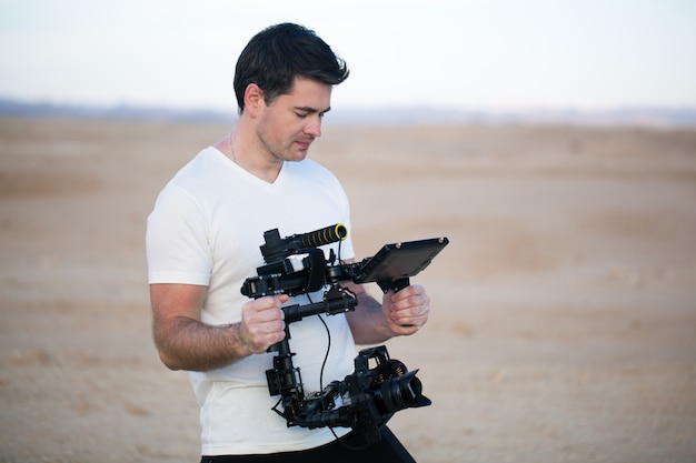 Young man using steadycam for shooting on beach