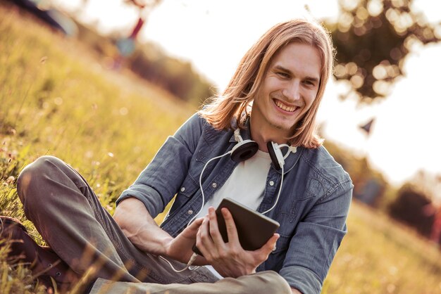 Young man using tablet in park with headphones