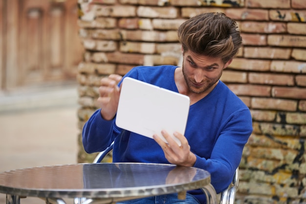 Young man using tablet pc as a mirror fixing hair 