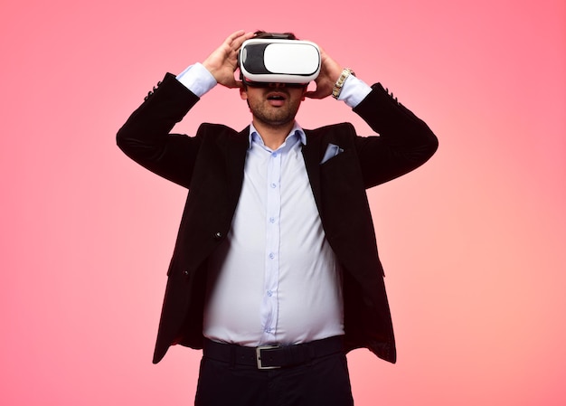 Young man using virtual reality headset. isolated on pink\
background studio portrait. vr, future, ga