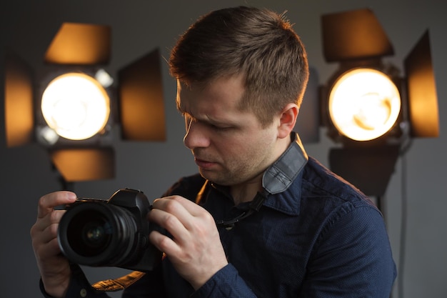 카메라 설정에 정통한 청년은 빛으로 작업하는 스튜디오에서 촬영