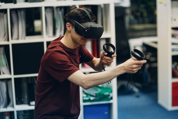 Young man in virtual reality goggles, vr glasses headset with joystick.