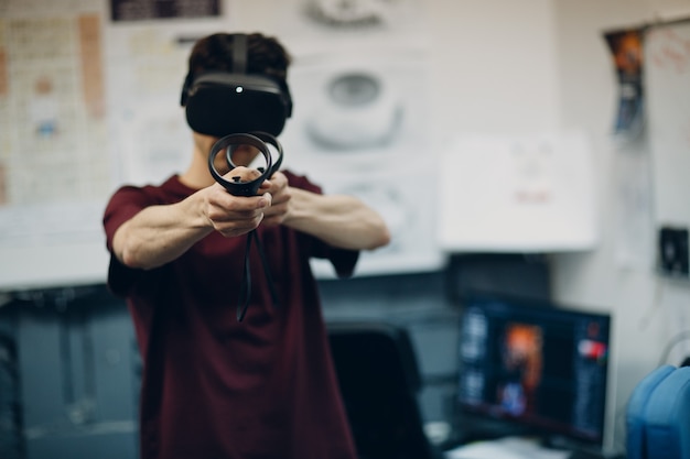 Young man in virtual reality goggles, vr glasses headset with joystick.