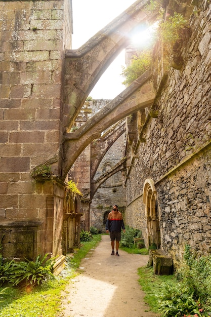 프랑스 브르타뉴 주 Cétes-d'Armor 주의 Paimpol 마을에 있는 Abbaye de Beauport의 내부 정원을 방문하는 청년. 프랑스