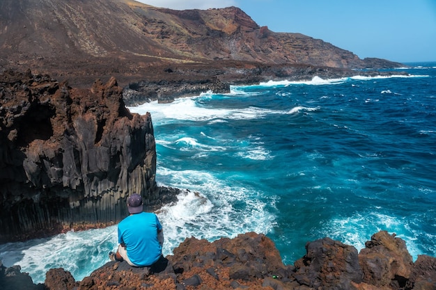 A young man on the volcanic trail in the town of Tamaduste on the coast of the island of El Hierro Canary Islands Spain vertical photo