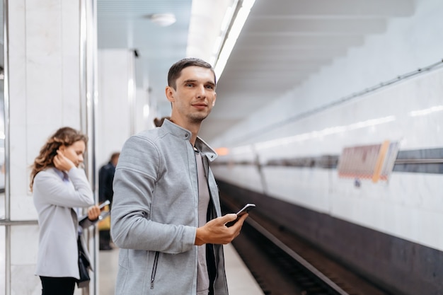 地下鉄のホームで電車を待つ若者