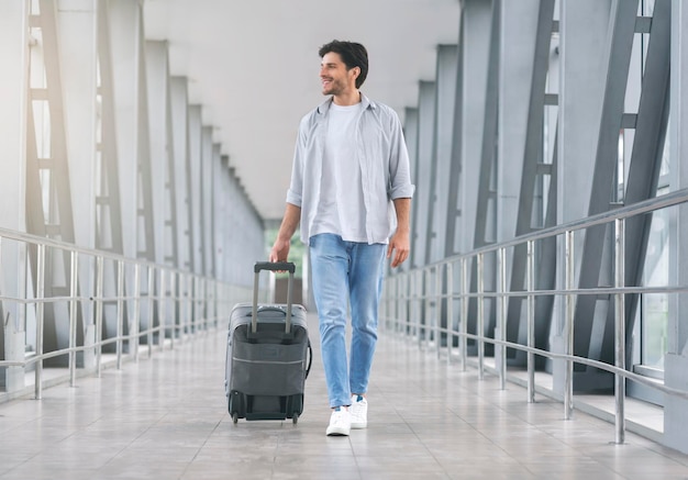 Giovane che cammina nella passerella dell'aeroporto con i bagagli