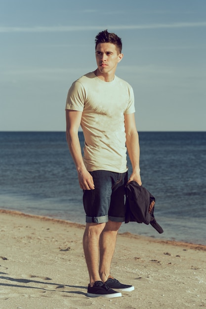 Young man walking along the seashore 