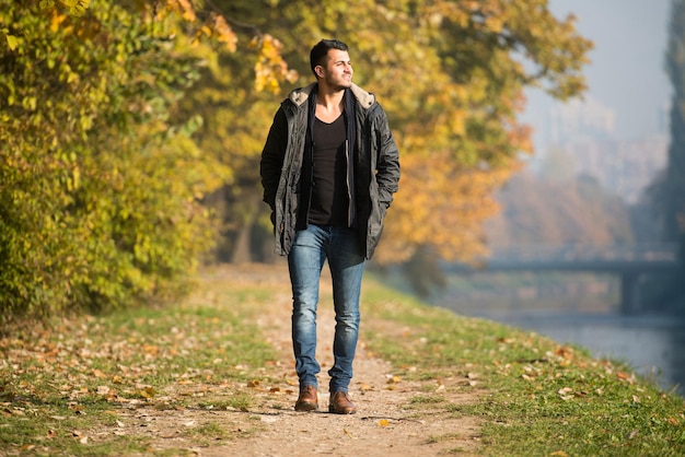 Young Man Walking In Autumn Forest