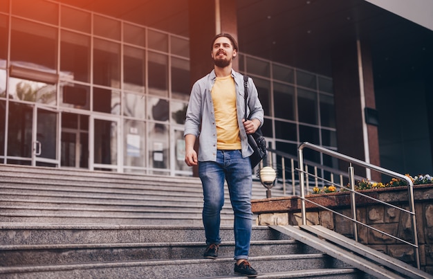 Young man walking down steps of university building