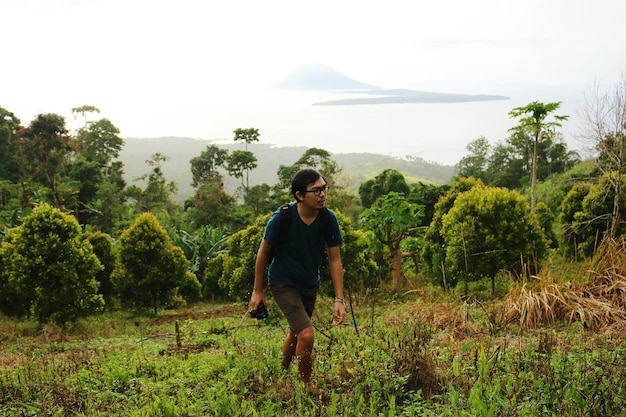 Young man walking on field against sky