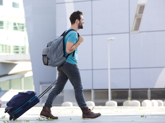 Young man walking outdoors with suitcase