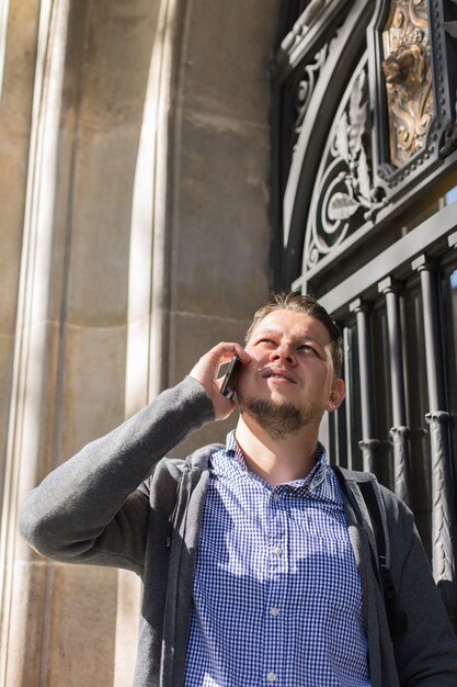 Young man walking on the street and talking by phone