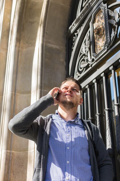 Young man walking on the street and talking by phone