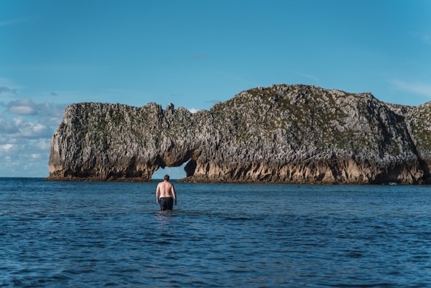 Photo young man walks in the water of the sea