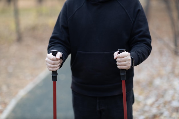 Young man walks with scandinavian walking sticks healthy\
lifestyle