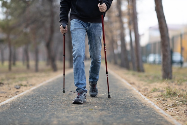 Young man walks with scandinavian walking sticks healthy\
lifestyle