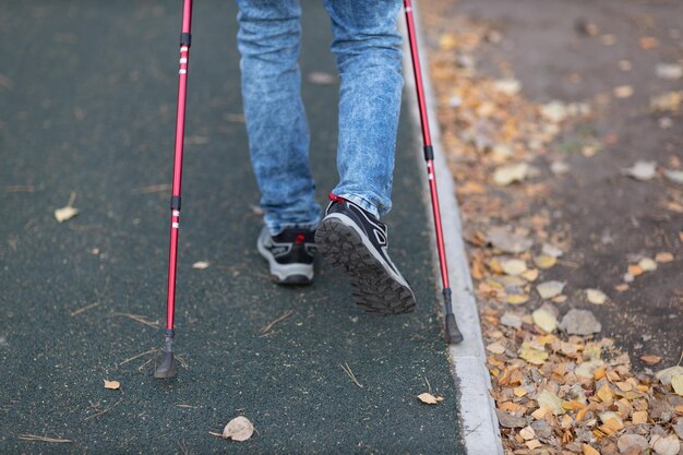 Young man walks with scandinavian walking sticks healthy\
lifestyle