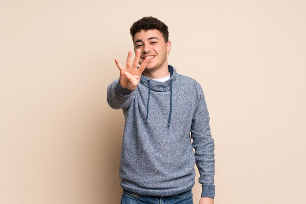 Young man  wall happy and counting four with fingers
