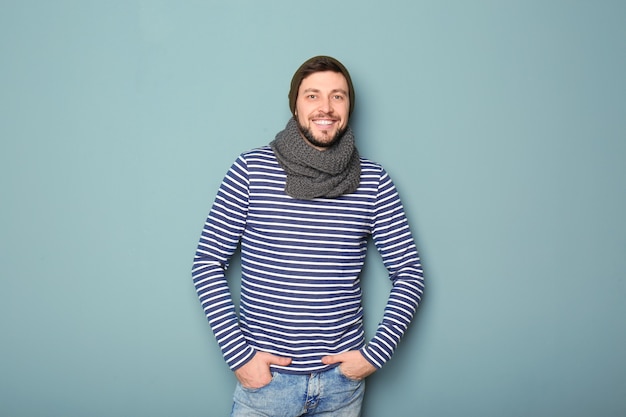 Young man in warm clothing on color wall.