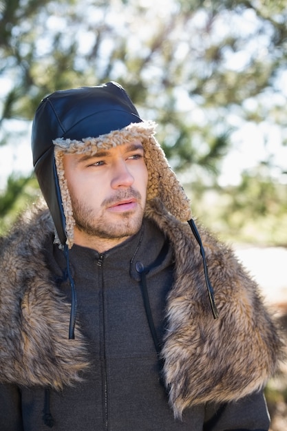 Photo young man in warm clothing looks to his side in forest